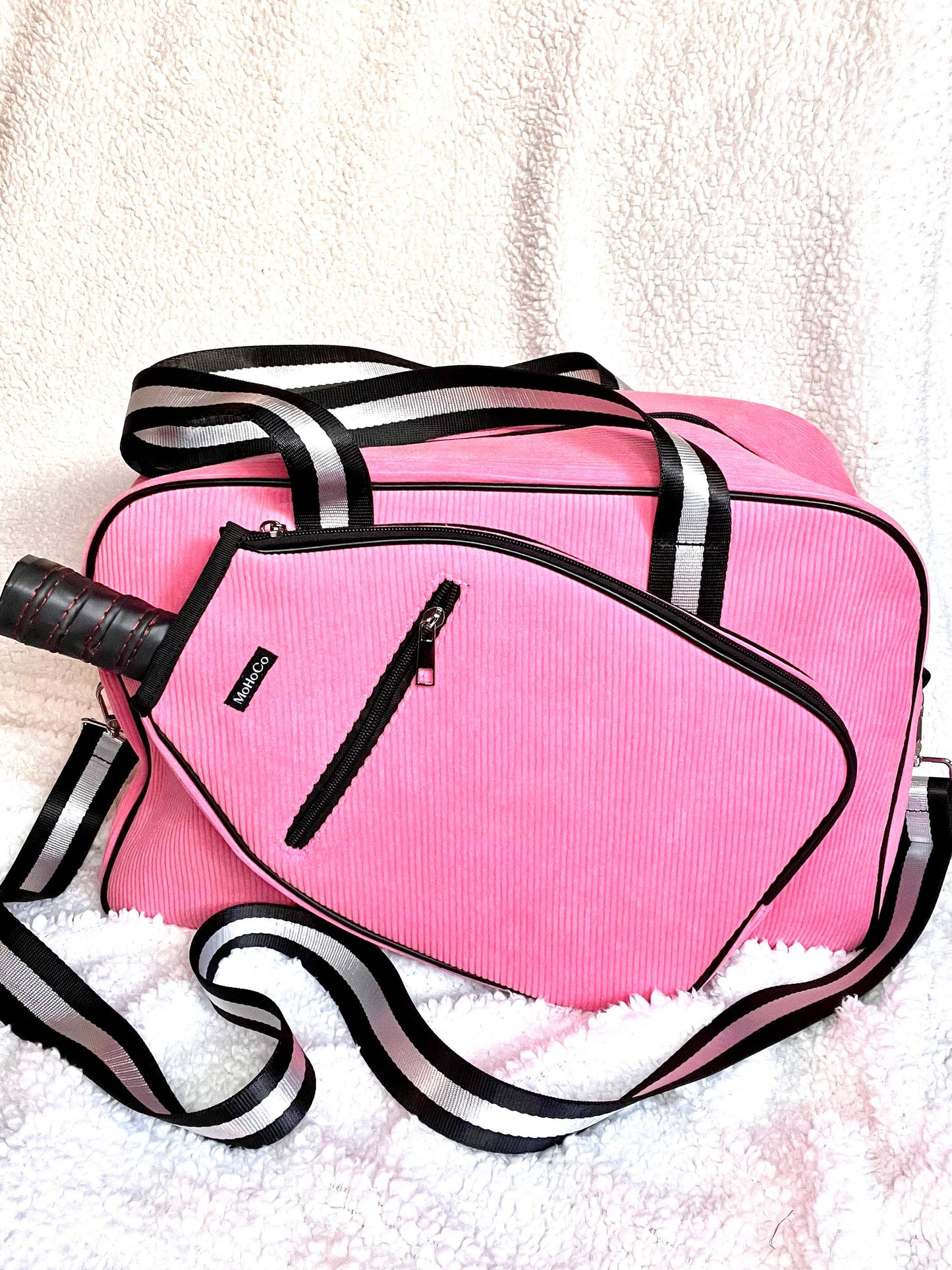 Pink duffel bag with black straps on a white textured surface