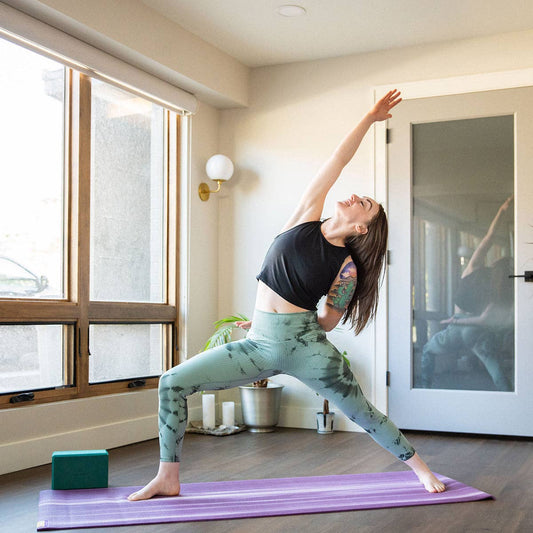 Woman practicing yoga in a home setting with large windows and a door.
