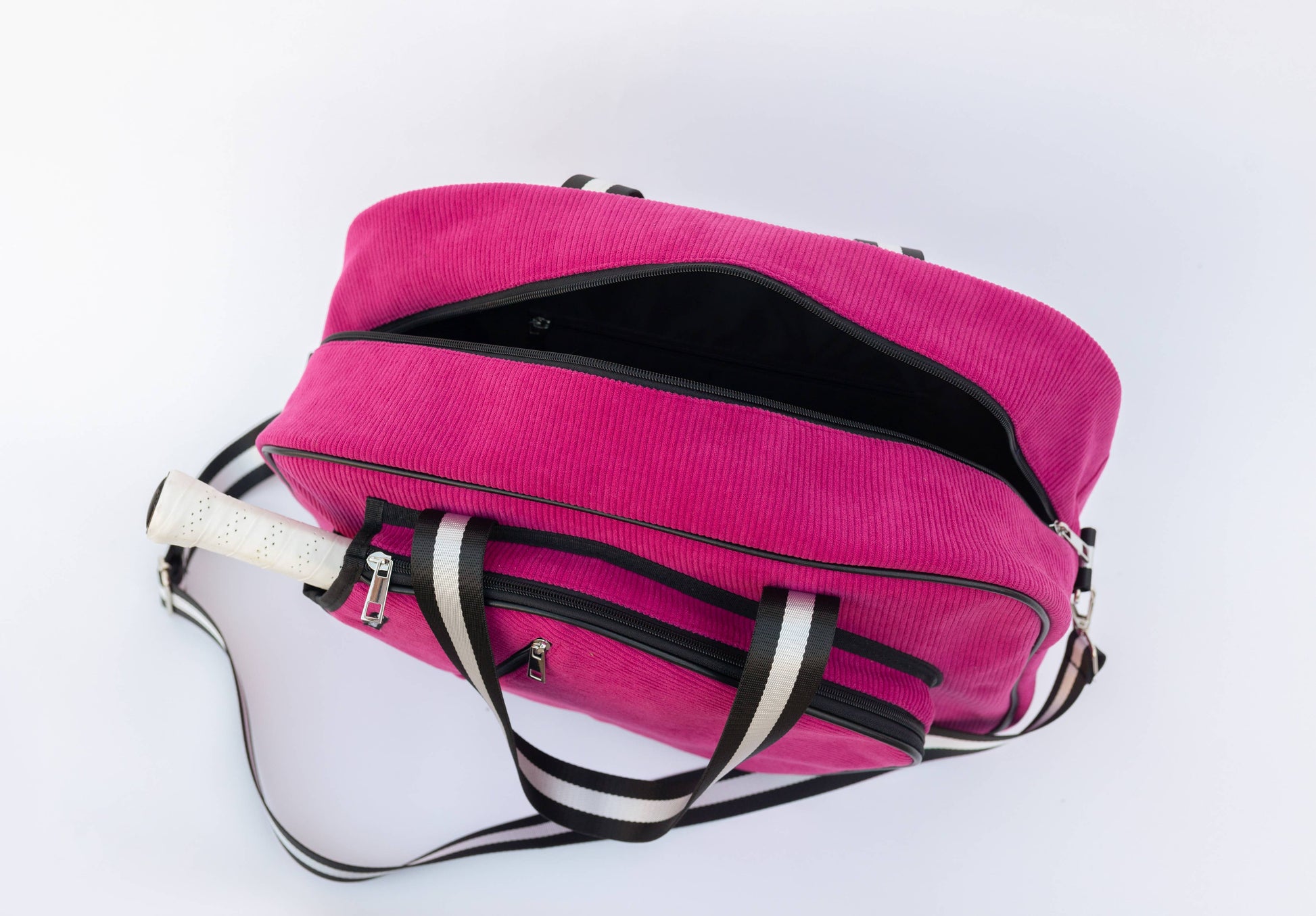 Pink duffel bag with black interior and white handles on a light gray background